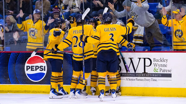 Quinnipiac men's ice hockey team members huddle on the ice in celebration