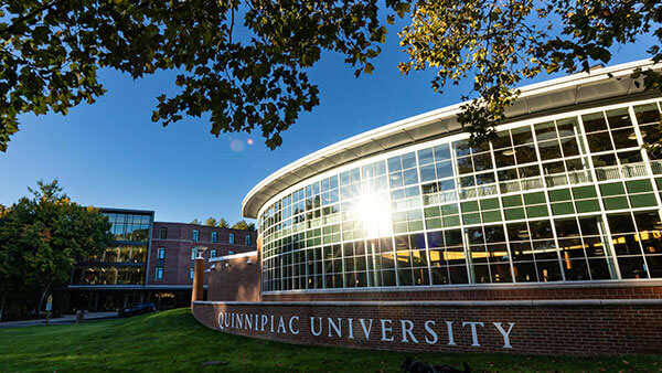 The sun shines behind the Carl Hansen Student Center and The Grove residence hall on Quinnipiac's Mount Carmel Campus.