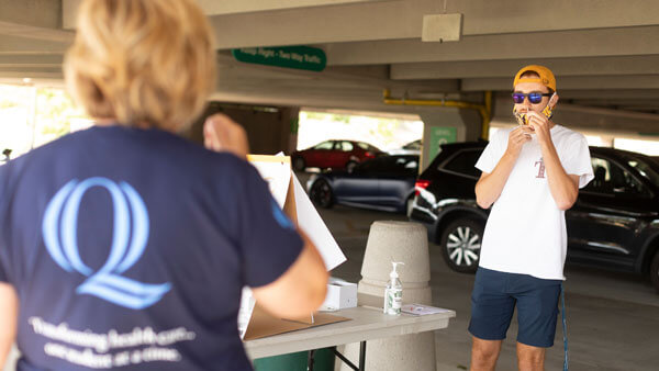 A volunteer assists a student self-administer a COVID nasal swab test