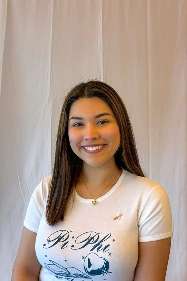 Headshot of Genesis Camejo, smiling and wearing a Pi Phi t-shirt and a gold necklace.