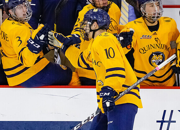 An ice hockey player high fives team mates during a game