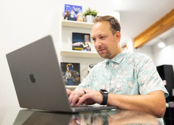 Man sitting down and working on his laptop at a desk