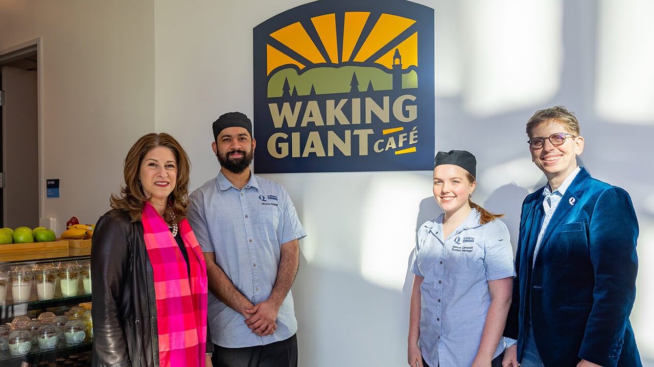 Provost, dean, and students in front of the Waking Giant Cafe sign