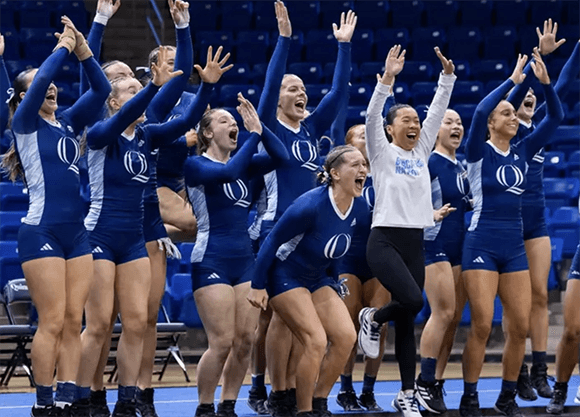 Members of the acrobatics and tumbling team cheer.