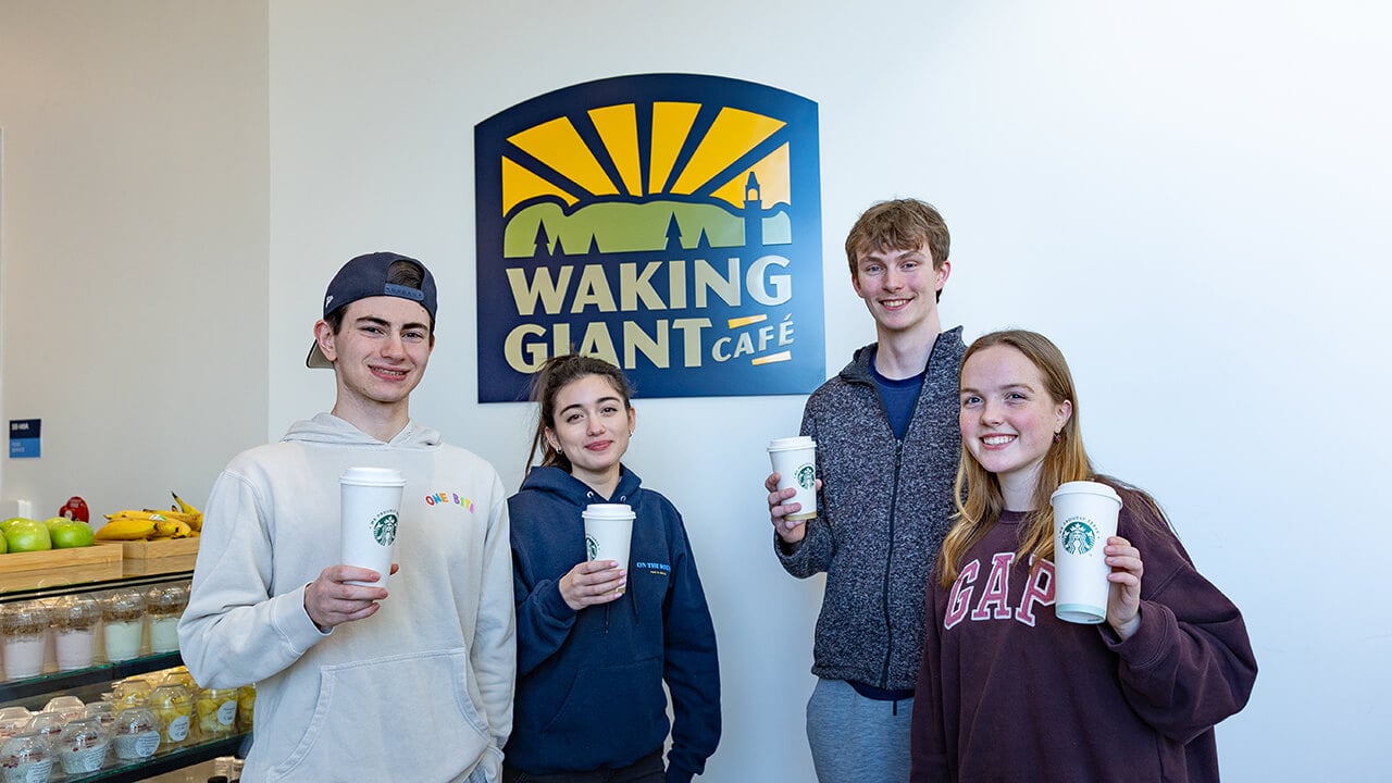 Students standing beside the Waking Giant Cafe sign