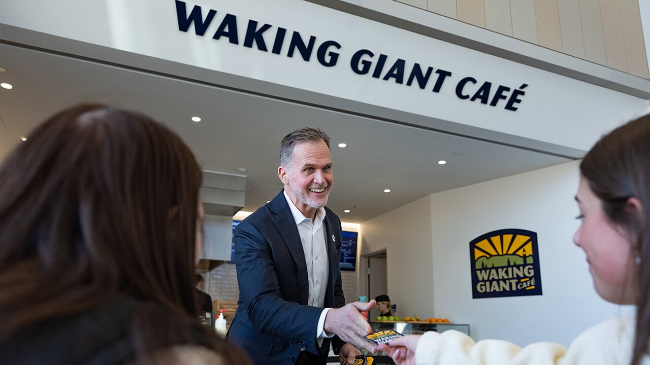 Staff and students smiling in front of the Waking Giant Cafe