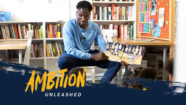 Abdulai Bundu reads a book to a group of children.