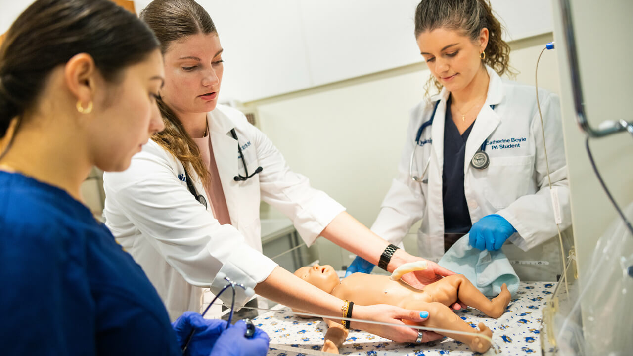 Nursing students participate in a birthing simulation with an infant mannequin