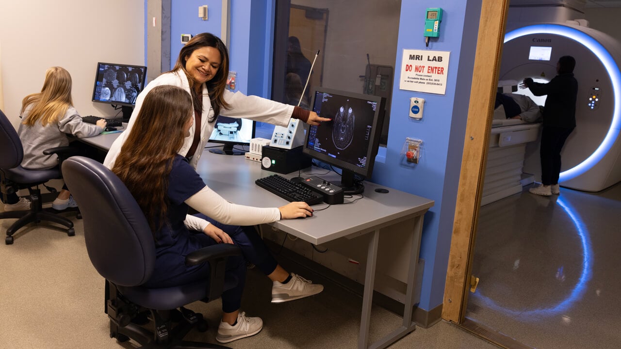 A professor instructs medical students using the MRI machine in the simulation lab.