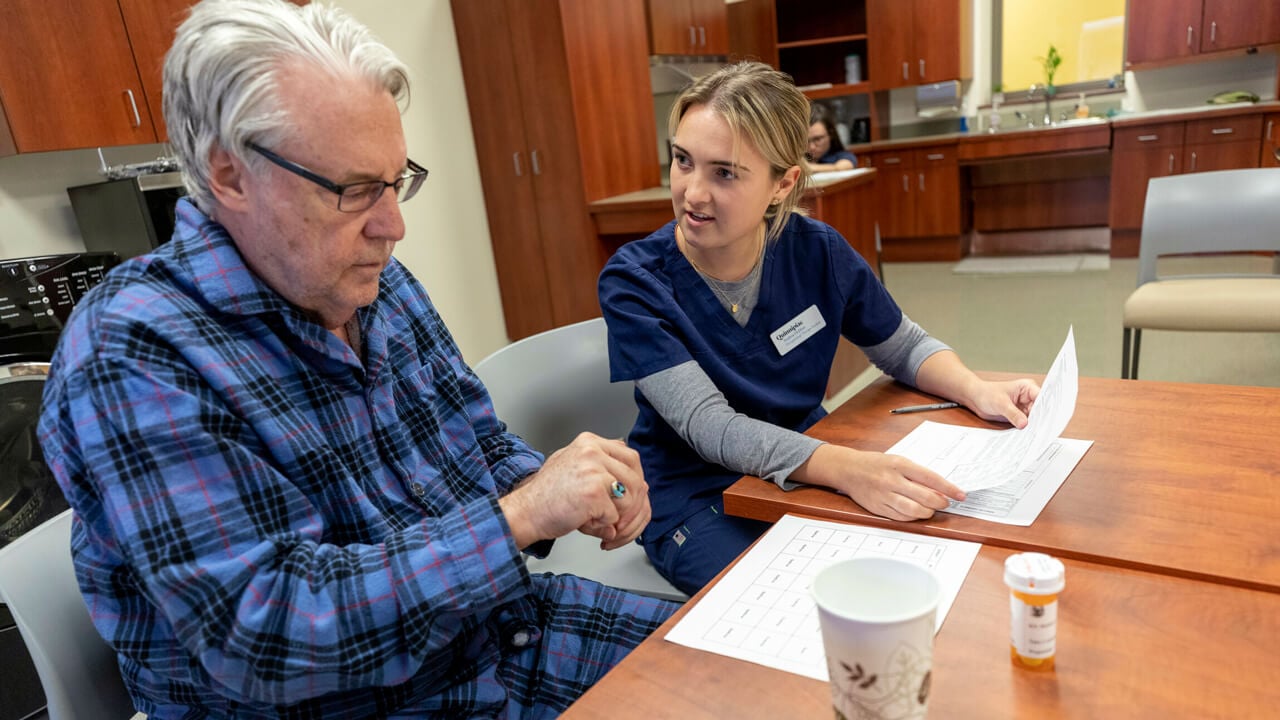 An occupational therapy student assists a standardized patient in the simulation suite.
