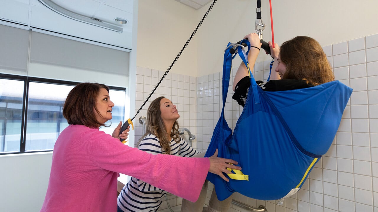 Occupational therapy students and professor demonstrate use of an accessibility device.