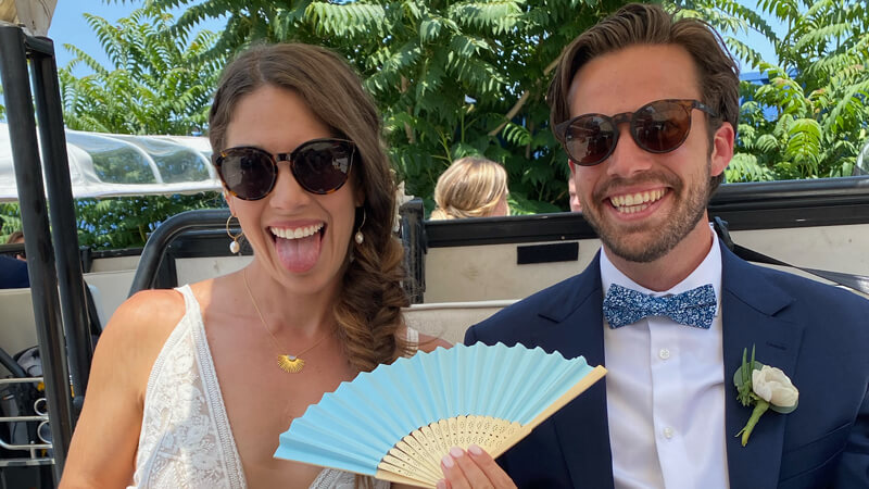Connor Gillivan and Lauren Zimniski smile and wave a blue fan from the back of a golf cart