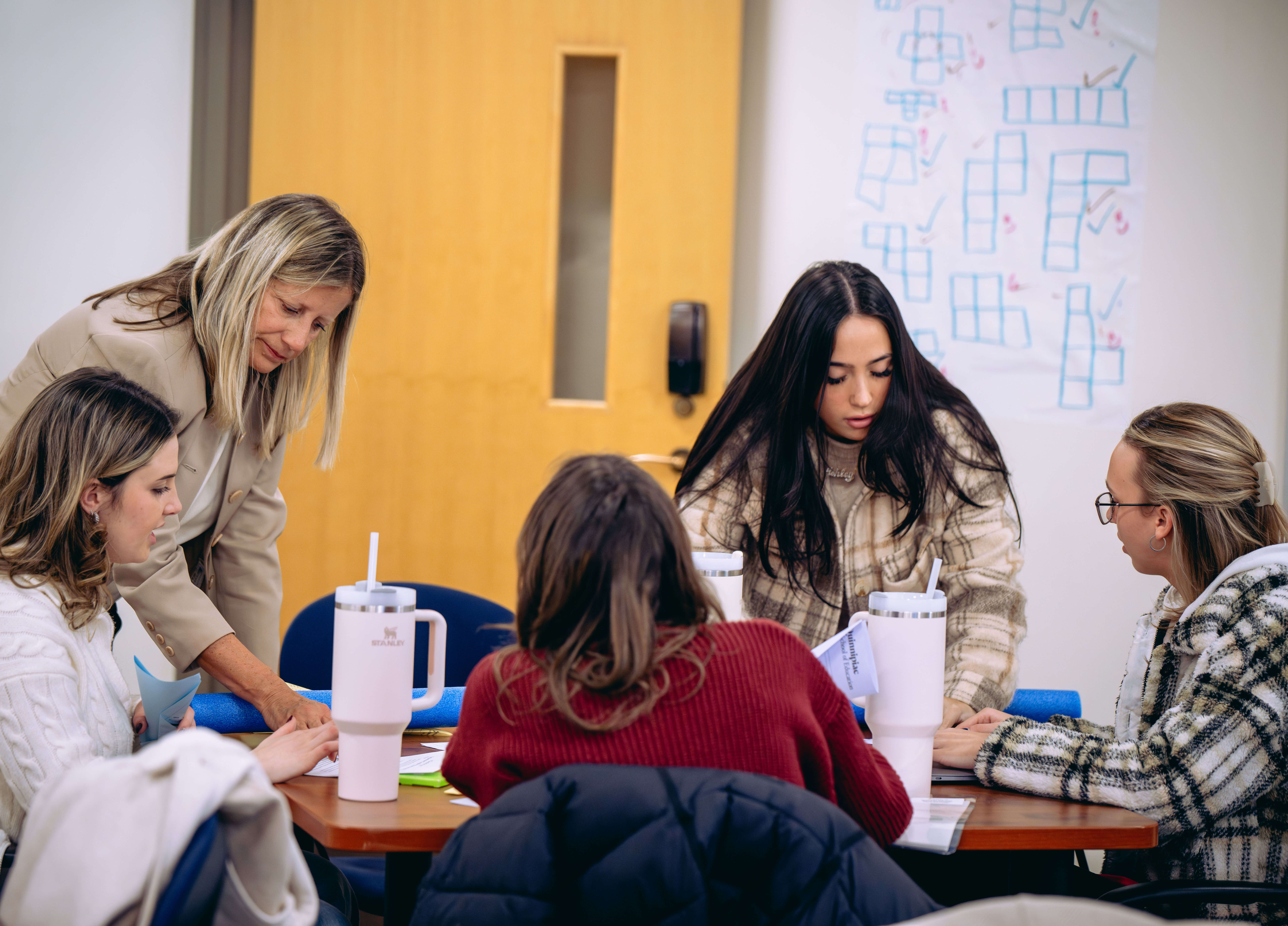 Students talking at a table with teacher in class