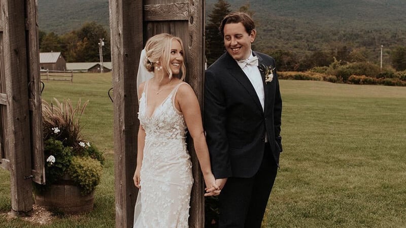 Shayna Zuk and Shane Garfi hold hands on a rolling farm landscape on their wedding day