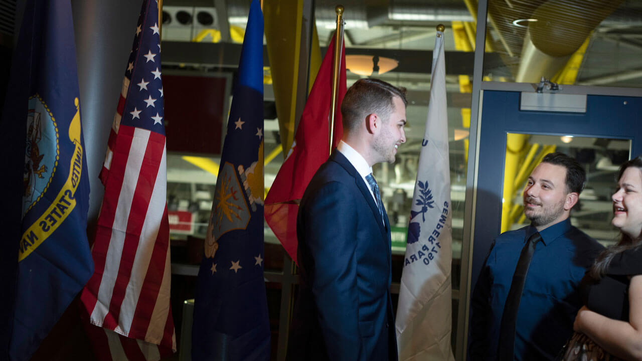 Three people standing together having a conversation in front of flags