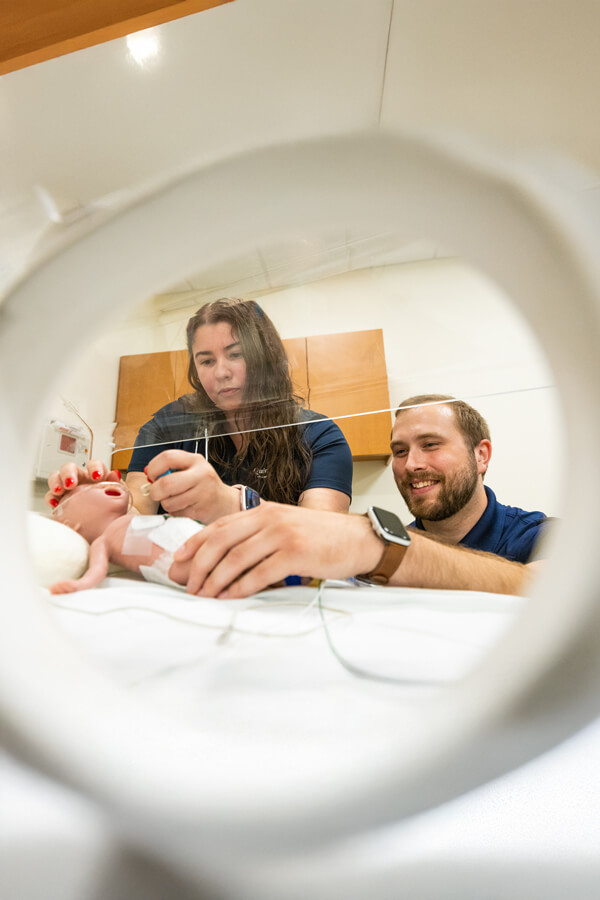 Occupational therapy students perform an exam on a mannequin infant in the simulation lab.