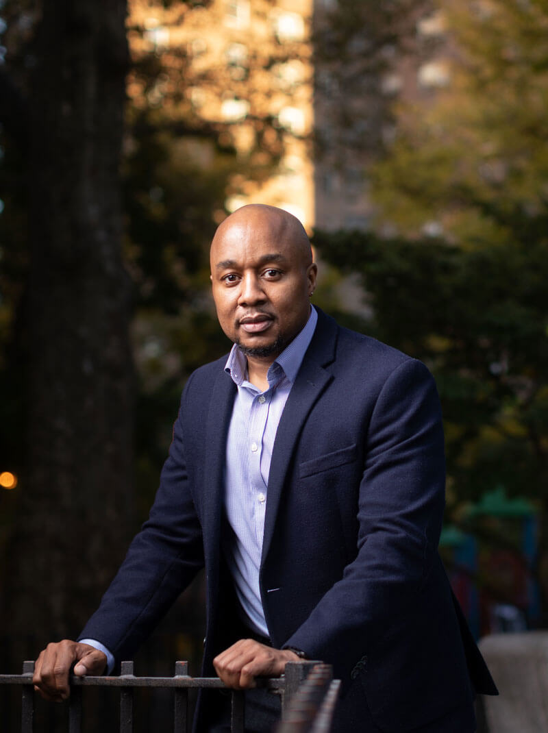 Don Sawyer in a Harlem neighborhood with the sun shining behind him