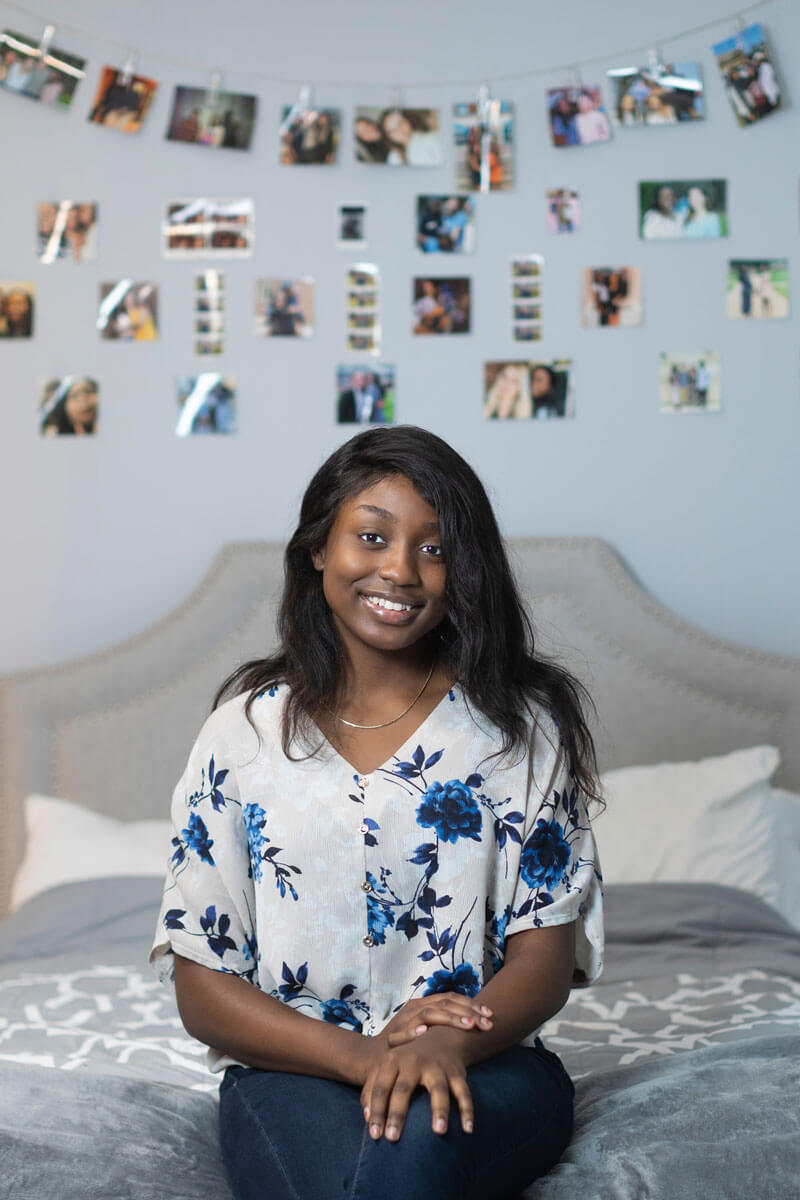 Olamide Gbotosho smiles as she sits in her bedroom