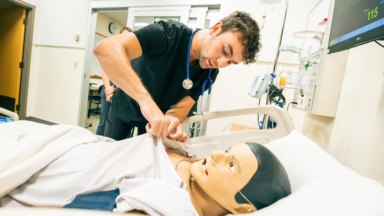 A male student checks the chest of a mannikin