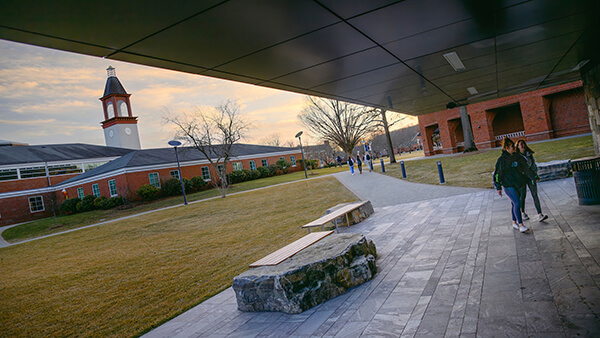 The Arnold Bernhard Library clocktower seen from the entrance of the Recreation and Wellness Center as 2 students walk by.