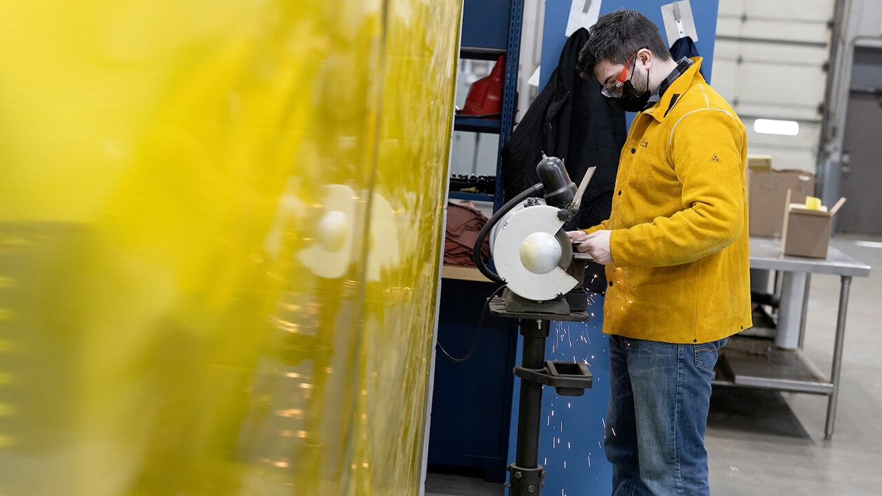 Student in safety goggles uses equipment.
