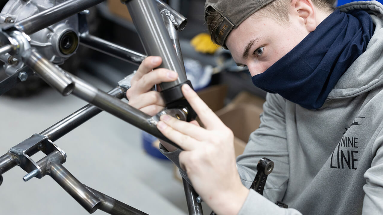 Student puts together frame of car.