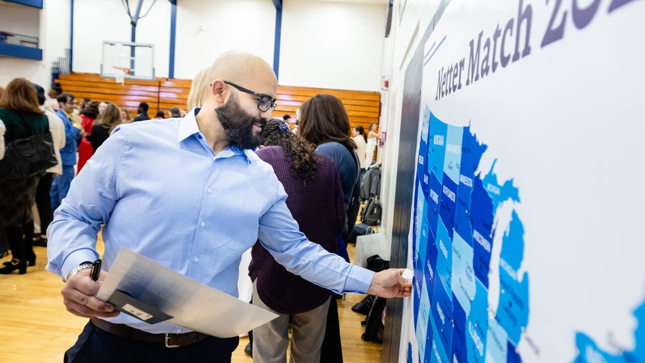 Alex Portillo places a pin at his medical match location on an oversized map of the United States