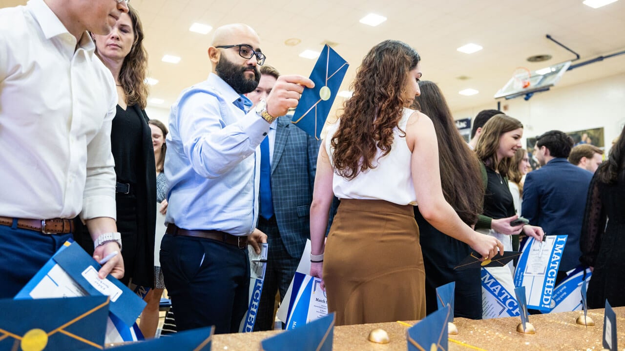 School of Medicine student holds up a blue envelope containing his placement