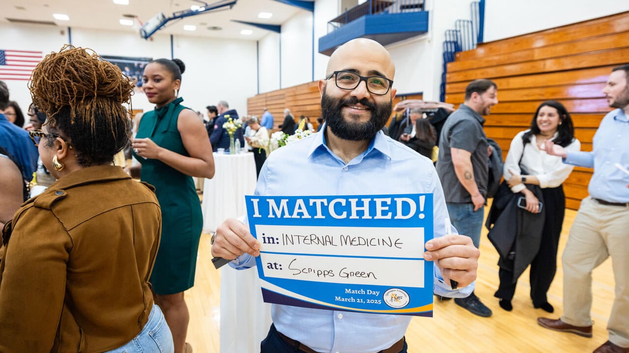 School of Medicine smiles while he holds an 'I Matched!' sign with his placement