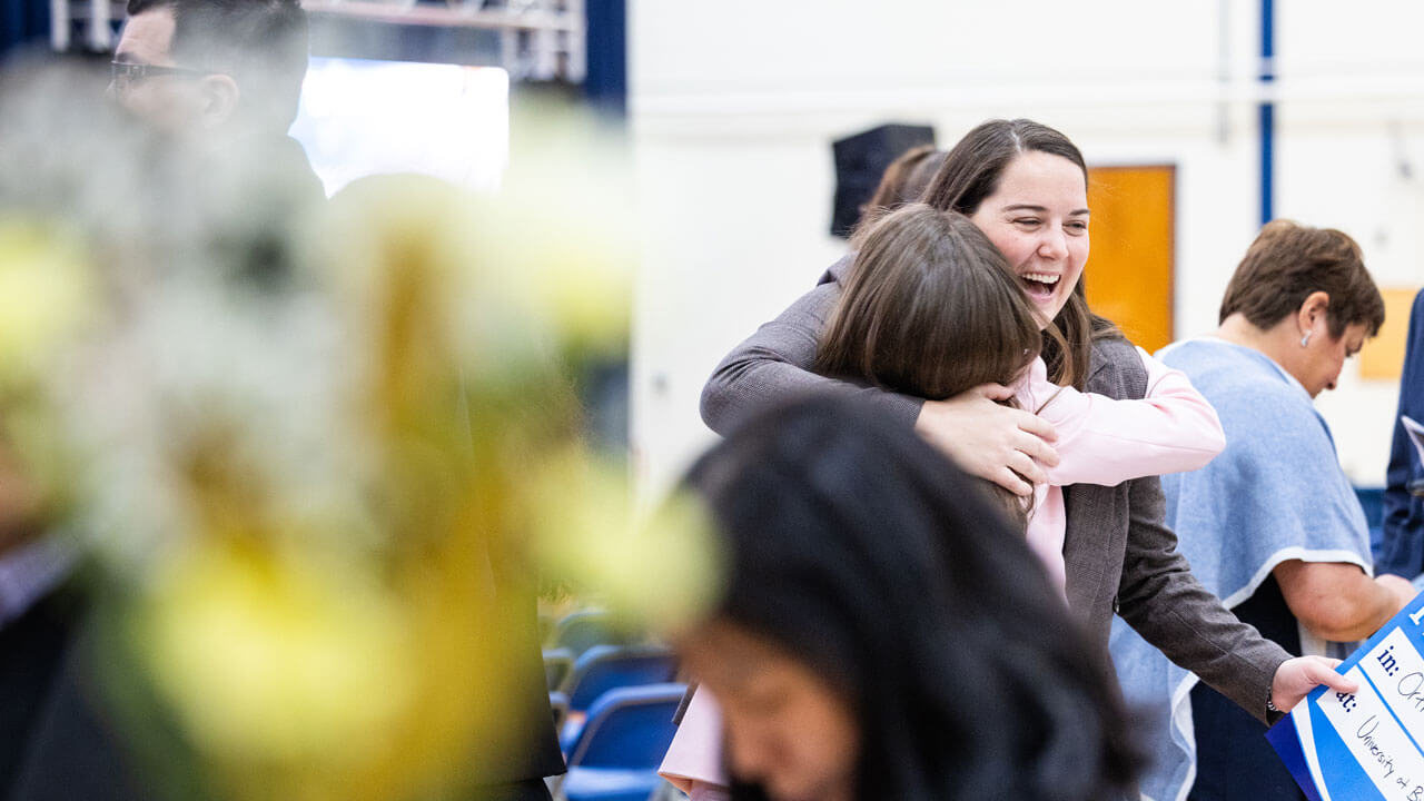School of Medicine student smiles while she hugs a loved one