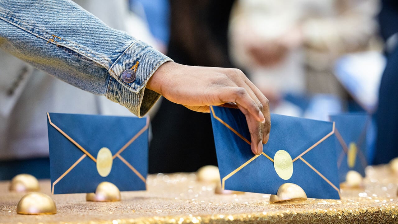 A hand reaches for a blue envelope on a table