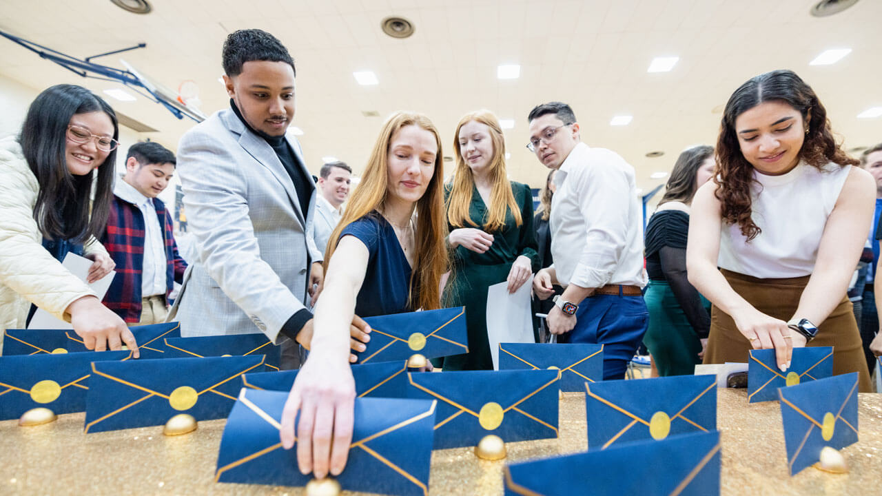 School of Medicine students eagerly reach for blue envelopes on a table