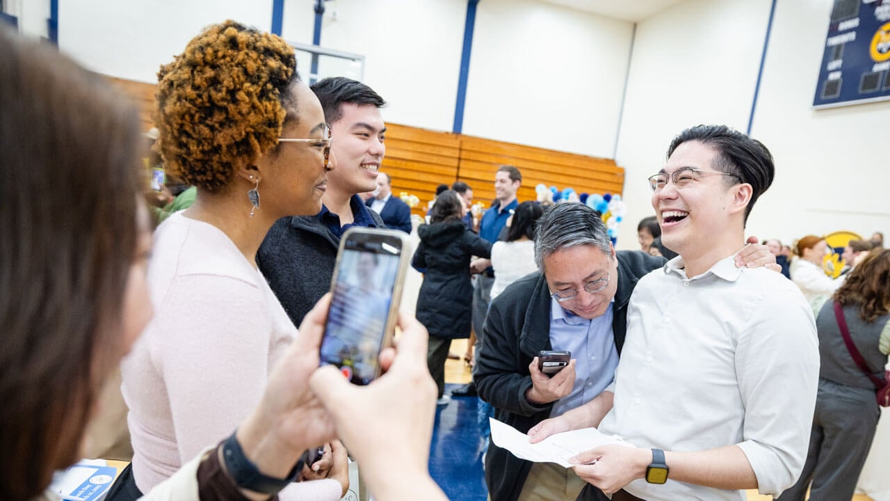 School of Medicine student smiles with his family and loved ones while opening his placement