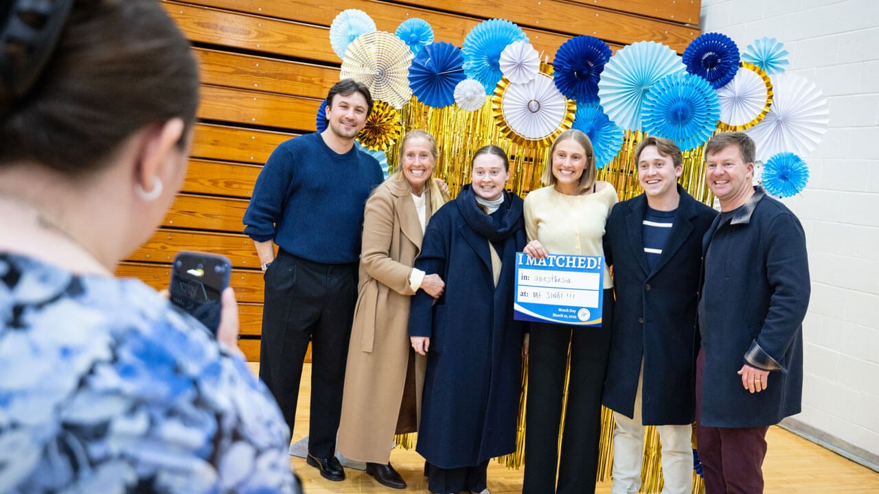 School of Medicine student smiles with loved ones while posing for a photo with a 'I Matched!' sign