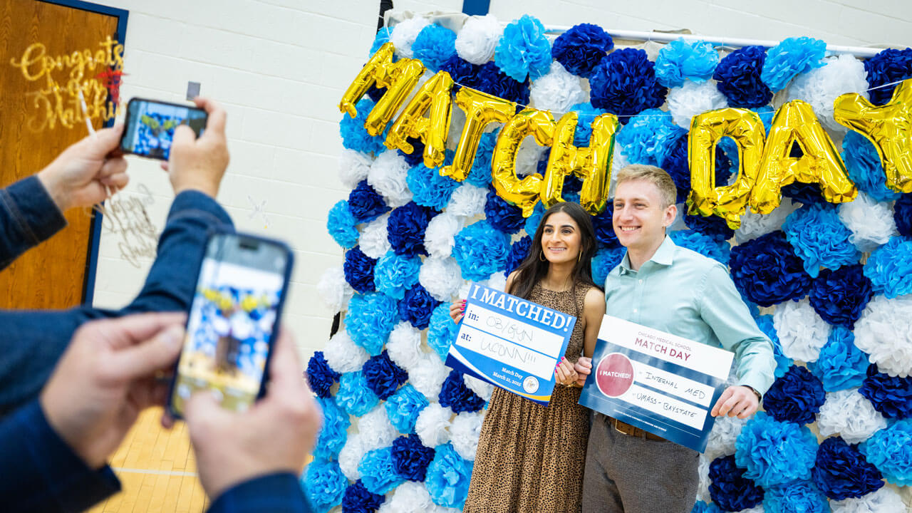 Loved ones take photos of School of Medicine students while they hold up an 'I Matched!' sign