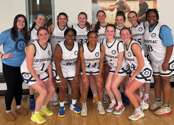 Club basketball team smiles for a photo at a tournament in uniform.