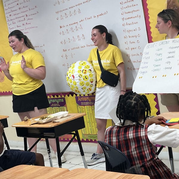 3 girls teaching a group of young students about dental health.