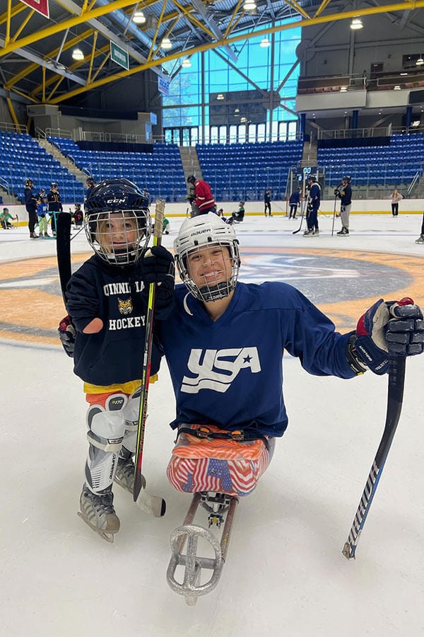 A young child with an adult who have both experienced limb loss, skating.