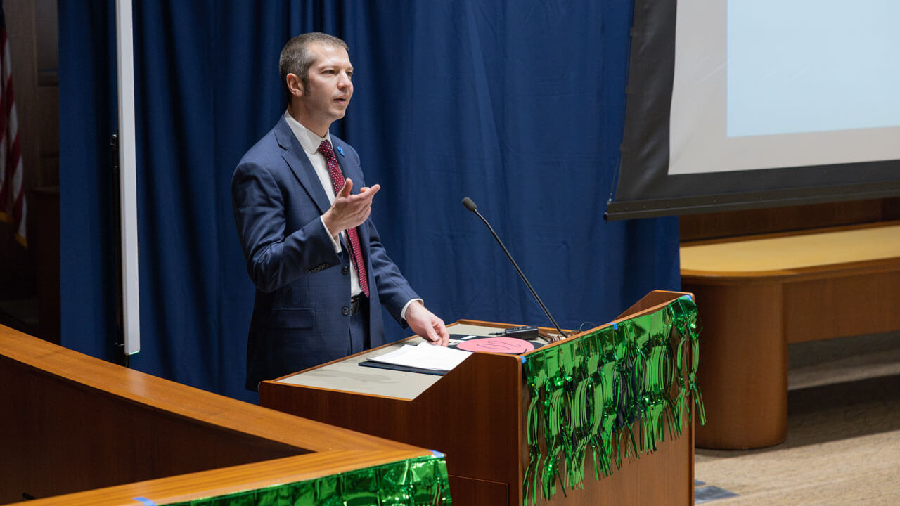 School of Law Dean, Brian Gallini, speak at podium at the PILP auction.