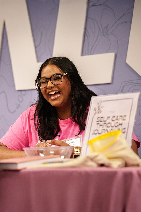 Student running a table for "self care through journaling"