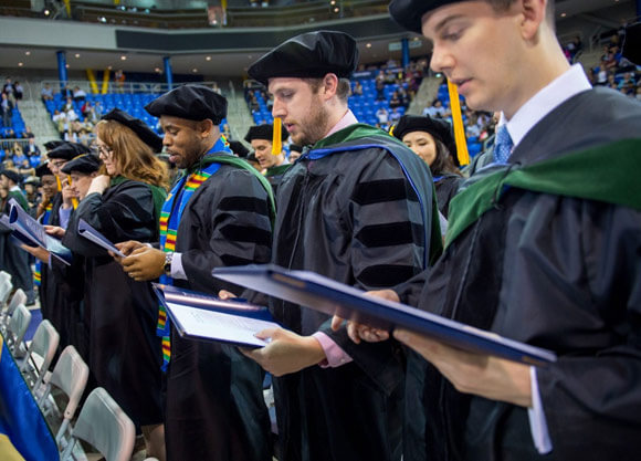 Medical students stand during a commencement ceremony