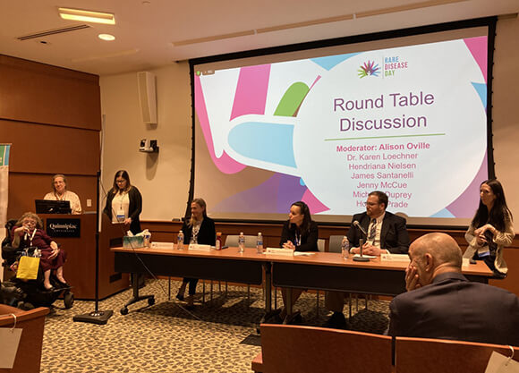 Presenters at rare disease day symposium talking to the crowd