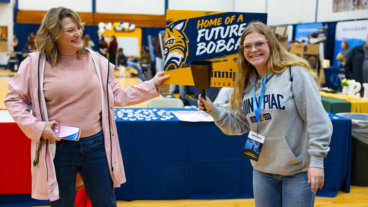 Two people pose for a photo holding a sign
