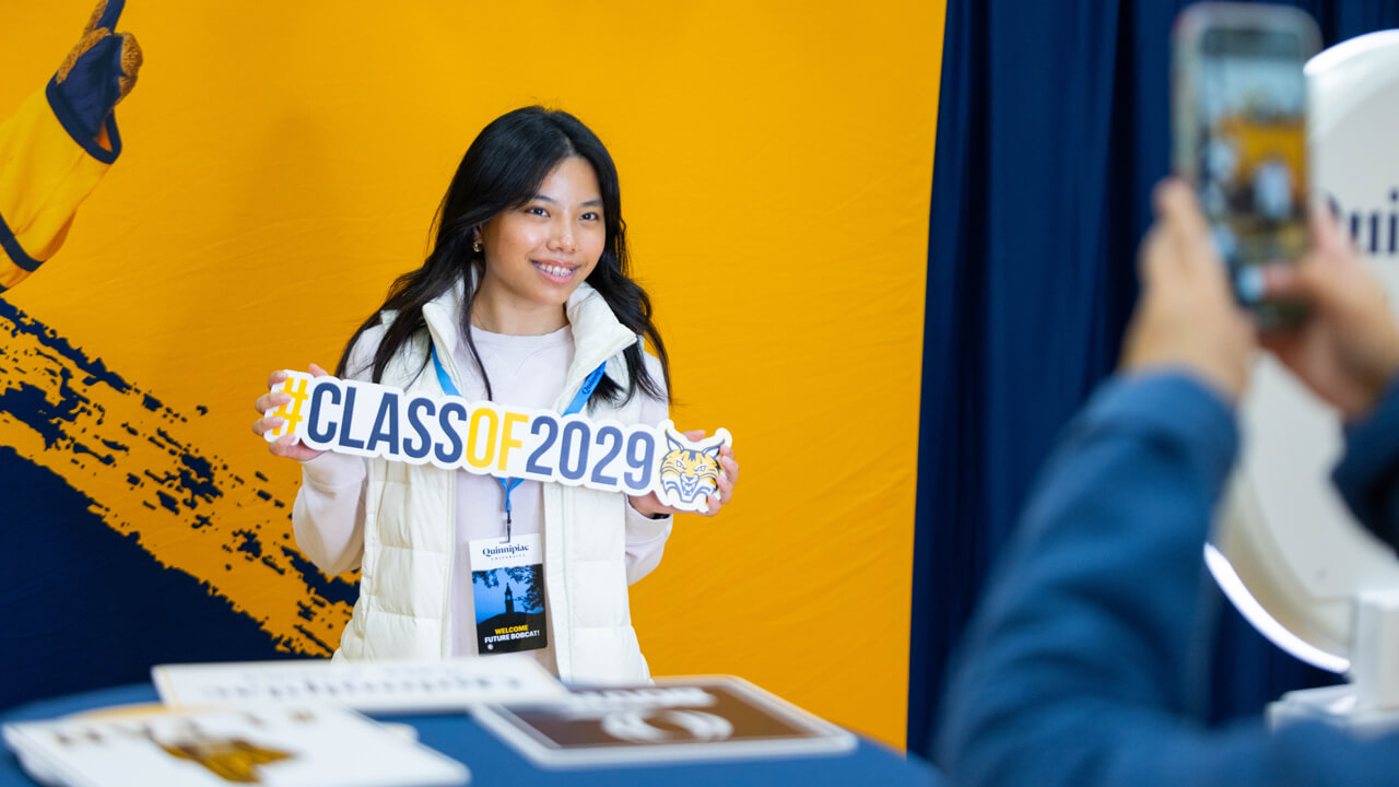 Individual poses for a photo holding a sign