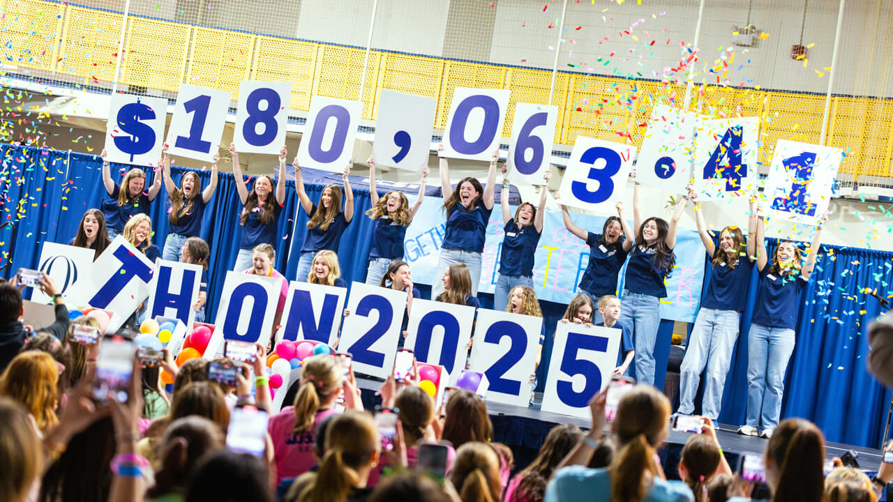 Students holding signs with the numbers 180,063