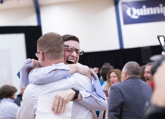 Brink and Dembowski hug, surrounded by loved ones.