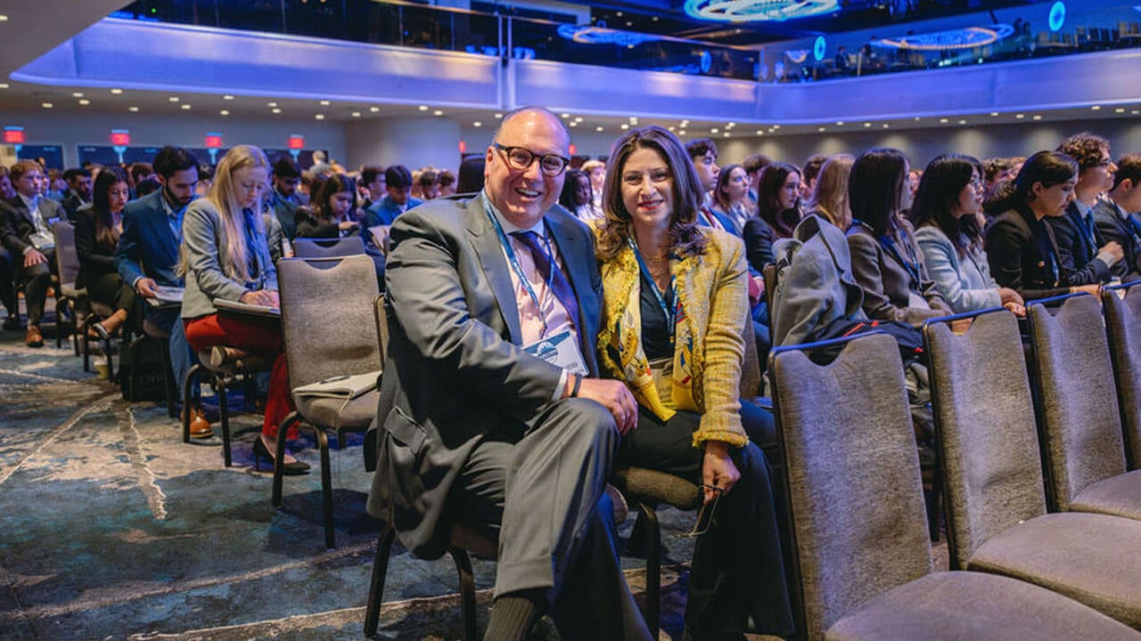 Two individuals smile for a photo in a crowd.