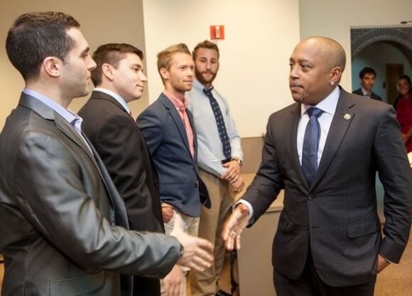 Daymond John of the entrepreneurship show Shark Tank shakes hands with several MBA students