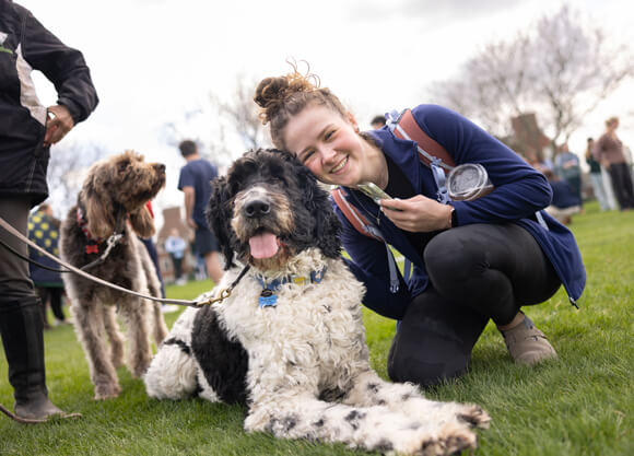 Individual poses for a photo with a black and white dog