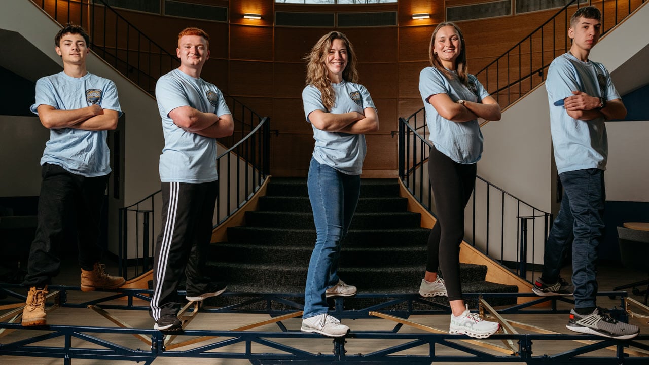 Five students pose while standing on the bridge